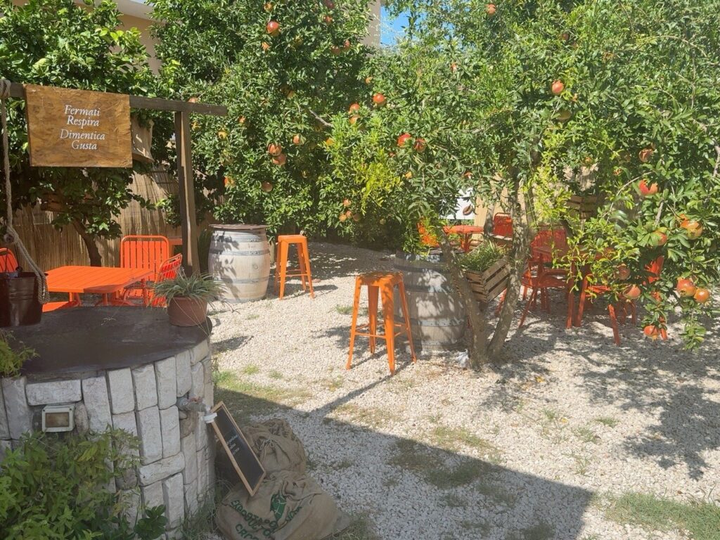 Tavolini arancioni, melograni e pozzo nel giardino Amnesia a Telese Terme
